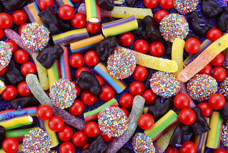 Bright colorful Halloween theme candy background with chocolate freckles, candy worms, orange and...
