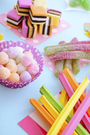 Pile of bright colorful candy on pale blue wood table for Halloween trick of treat or childrens...
