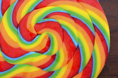 Bright rainbow lollipop candy on dark wood table.の写真素材