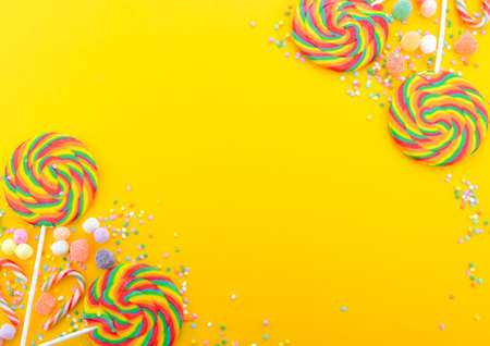 Bright rainbow lollipop candy on colorful yellow wood table for Halloween Trick or Treat or Childrens Party.の写真素材