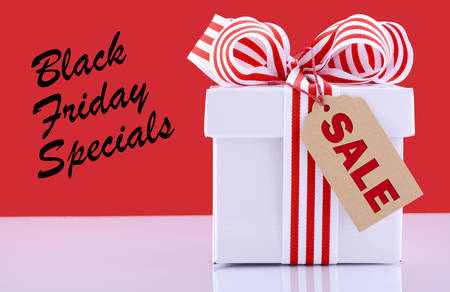 Black Friday red and white sales promotion gift box on white reflective table against a red...