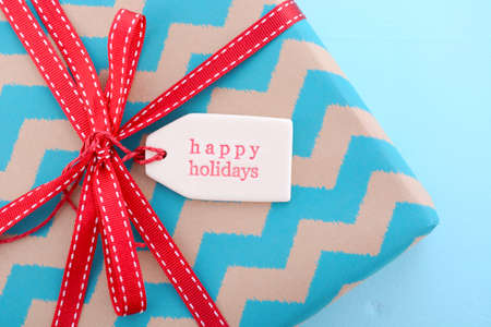 Festive Christmas red and aqua blue gift with  Happy Holidays gift tag on pale blue wood table.の写真素材