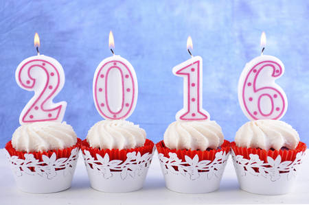 Happy New Year cupcakes with lit 2016 candles on white table against a blue background.の写真素材