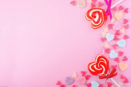 Happy Valentines Day Background with candy and red heart shape lollipops on pink wood background.の写真素材