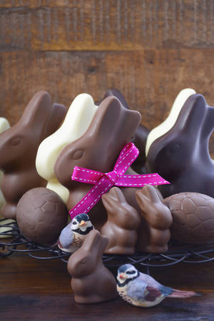 Family of milk, dark and white chocolate bunny Easter eggs on vintage baking rack against a dark...