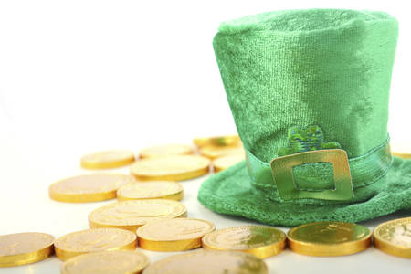 St Patricks Day leprechaun hat with chocolate gold covered coins on white wood backround.の写真素材