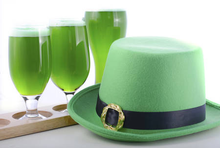 St Patricks Day line up of of glasses of green beer with leprechaun hat on a white wood table background.の写真素材