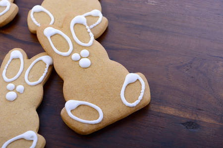 Happy Easter gingerbread cookie bunnies on a dark wood table background, closeup with copy space.の写真素材
