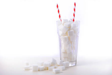 Soda glass of white sugar cubes with red and white straws on white wooden tableの写真素材