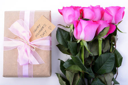 Happy Mothers Day brown paper gift and pink roses on white wood table.の写真素材