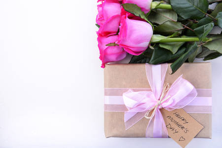 Happy Mothers Day brown paper gift and pink roses on white wood table, with copy space.の写真素材