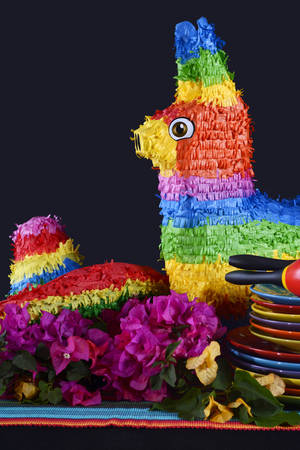 Colorful Happy Cinco de Mayo party table with rainbow straw donkey and sombrero pinata against a black background.の写真素材