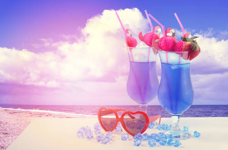 Summer is Here theme Blue Hawaiian cocktails with pink flamingo straws and quirky sunglassesの写真素材