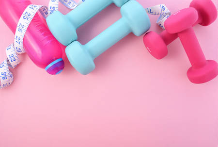 Health and fitness concept with pink and blue dumbells and accessories on a pink wood table, with copy space.の写真素材