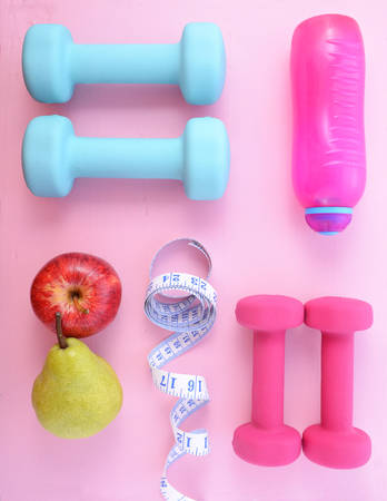 Health and fitness flat lay with pink and blue dumbells and accessories on a pink wood table.の写真素材