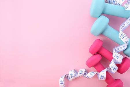 Health and fitness concept with pink and blue dumbells and accessories on a pink wood table, with copy space.の写真素材