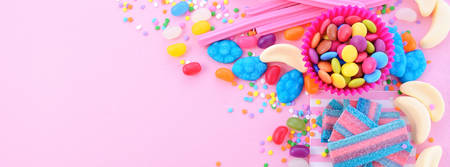 Bright colorful candy background on pink wood table for Halloween trick of treat or childrens birthday party favors, sized to fit a popular social media cover image placeholder.の写真素材