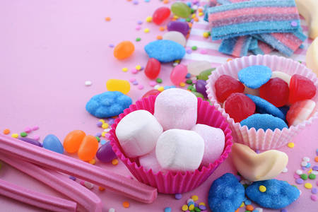 Bright colorful candy background on pink wood table for Halloween trick of treat or childrens birthday party favors, closeup.の写真素材