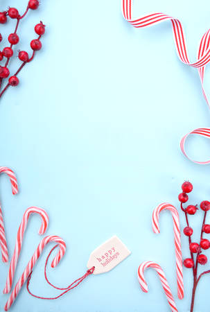 Festive Christmas background with decorated borders of red and white candy canes, bon-bons, berries...