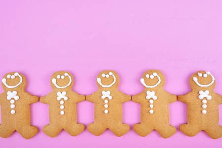 Festive modern pink theme Christmas holiday background with gingerbread cookies on pink wood table.の写真素材
