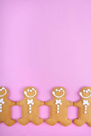Festive modern pink theme Christmas holiday background with gingerbread cookies on pink wood table.の写真素材