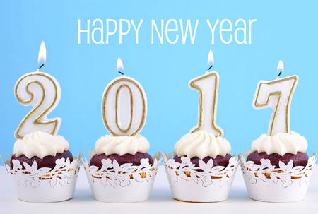 Happy New Year cupcakes with 2017 candles in a blue, gold and white winter theme setting background