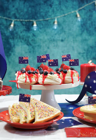 Australian theme party table with flags and iconic food including mini pavlovas, lamingtons, meat pies and fairy bread.