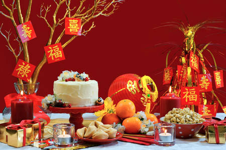 Chinese New Year party table in red and gold theme with food and traditional decorations.の写真素材