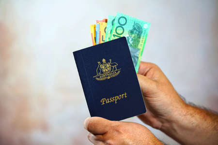 Man putting Australian cash money into an Australian passport, with copy spaceの写真素材
