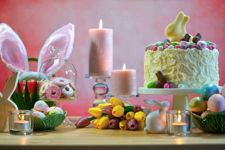 Happy Easter party table with white chocolate bunny novelty cake against a pink background.の写真素材