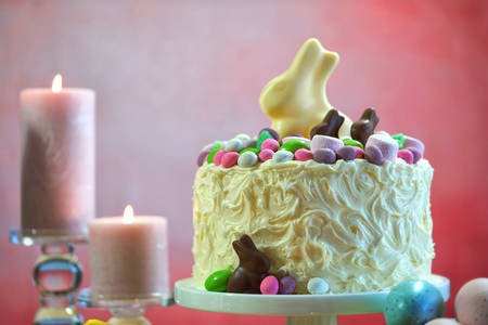 Happy Easter white chocolate bunny novelty cake against a pink background.