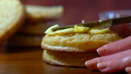 Hot Australian English style breakfast crumpets macro closeup, female hands spreading butter.の写真素材