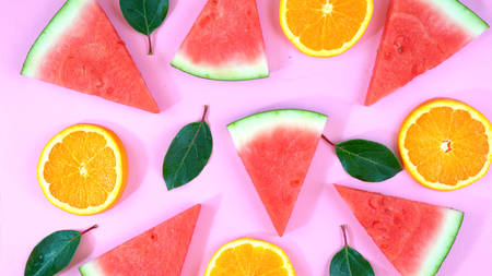 Watermelon and orange slices knolling flat lay on pink wood table overhead.の写真素材