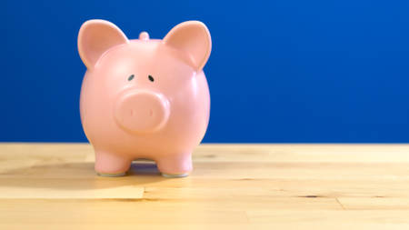 Piggy bank on counter against blue background with copy space.の写真素材