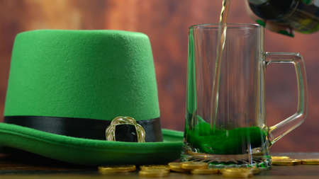 St Patricks Day pouring green beer with green leprechaun hat and gold covered chocolate coins...
