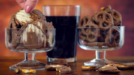 Sweet and salty chocolate covered salt and vingear potato chips and pretzels with cola drink, on rustic wood background.の写真素材