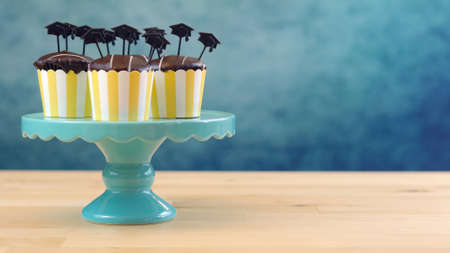 Yellow and blue theme graduation party cupcakes with cap hats toppers and decorations.の写真素材