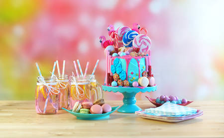 On-trend candyland fantasy drip cake for childrens, teens birthday, anniverary, mothers day and valentines day celebrations. in party table setting with mason jars pink lemonade.の写真素材