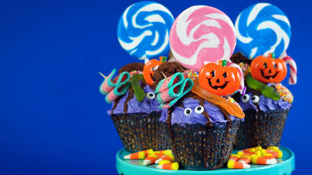 Happy Halloween candyland drip cake style cupcakes with lollipops and candy on blue background.の写真素材