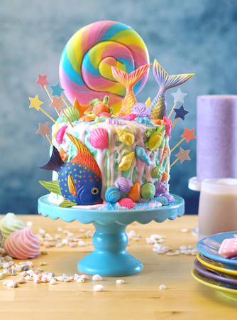 Mermaid theme candyland cake with colorful glitter tails, shells and sea creatures toppers for childrens, teens, novelty birthday and party celebrations.の写真素材