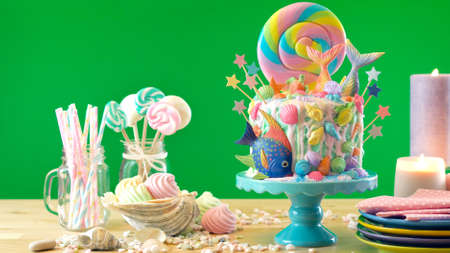 Mermaid theme candyland cake with colorful glitter tails, shells and sea creatures toppers for childrens, teens, novelty birthday and party celebrations, green background.の写真素材