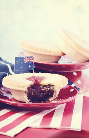 Traditional Australian Meat Pies for Australia or Anzac Day holiday party food, in red, white and blue setting with copy space, with applied vintage wash filter.の写真素材