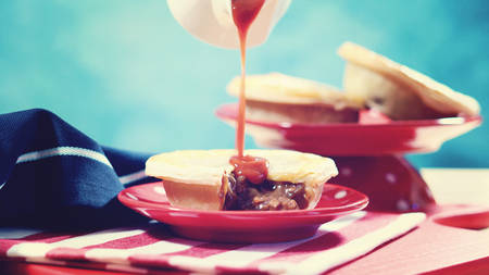 Traditional Australian Meat Pies for Australia or Anzac Day holiday party food, in red, white and blue table setting, with applied vintage wash filter.の写真素材