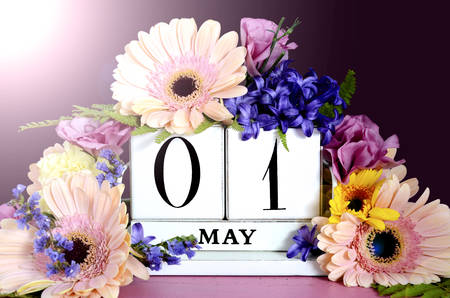 Happy May Day vintage wood calendar decorated with Spring flowers on pink wood table with dark...