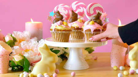 Easter theme candy land drip cupcakes decorated with chocolate bunnies in party table setting.の写真素材