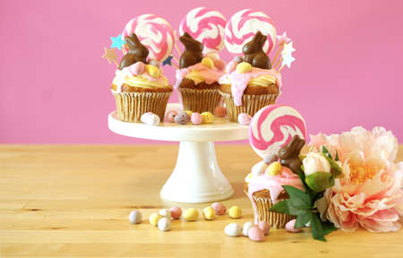 Easter theme candy land drip cupcakes decorated with chocolate bunnies in party table setting.