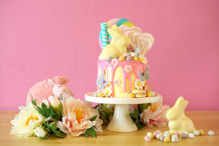 On-trend Easter theme candy land drip cake decorated with lollipops, candy eggs and white chocolate...