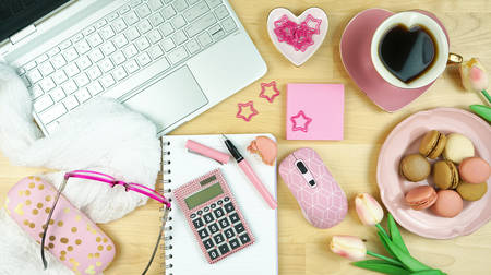 Feminine desk and workspace with modern touch-screen laptop with pink accessories flatlay overhead.の写真素材
