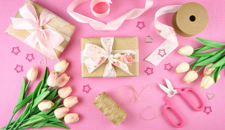 Gifts wrapped in kraft paper and pink ribbons overhead flat lay for Mothers Day, birthday or...