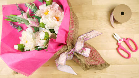 Flowers wrapped in pink tissue and hessian modern trend wrapping flat lay for Mothers Day, birthday or Valentines Day celebrations.の写真素材